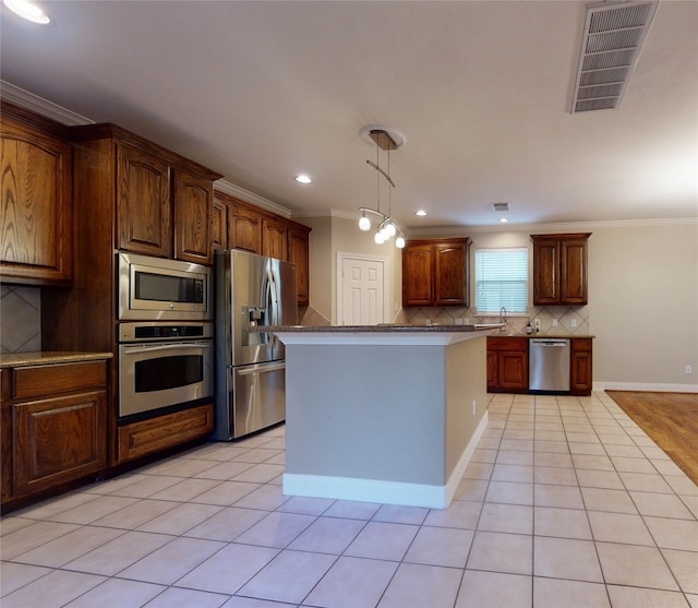 kitchen featuring a center island, stainless steel appliances, tasteful backsplash, a notable chandelier, and ornamental molding