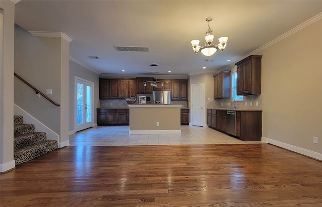 kitchen with a center island, light wood-type flooring, ornamental molding, and appliances with stainless steel finishes