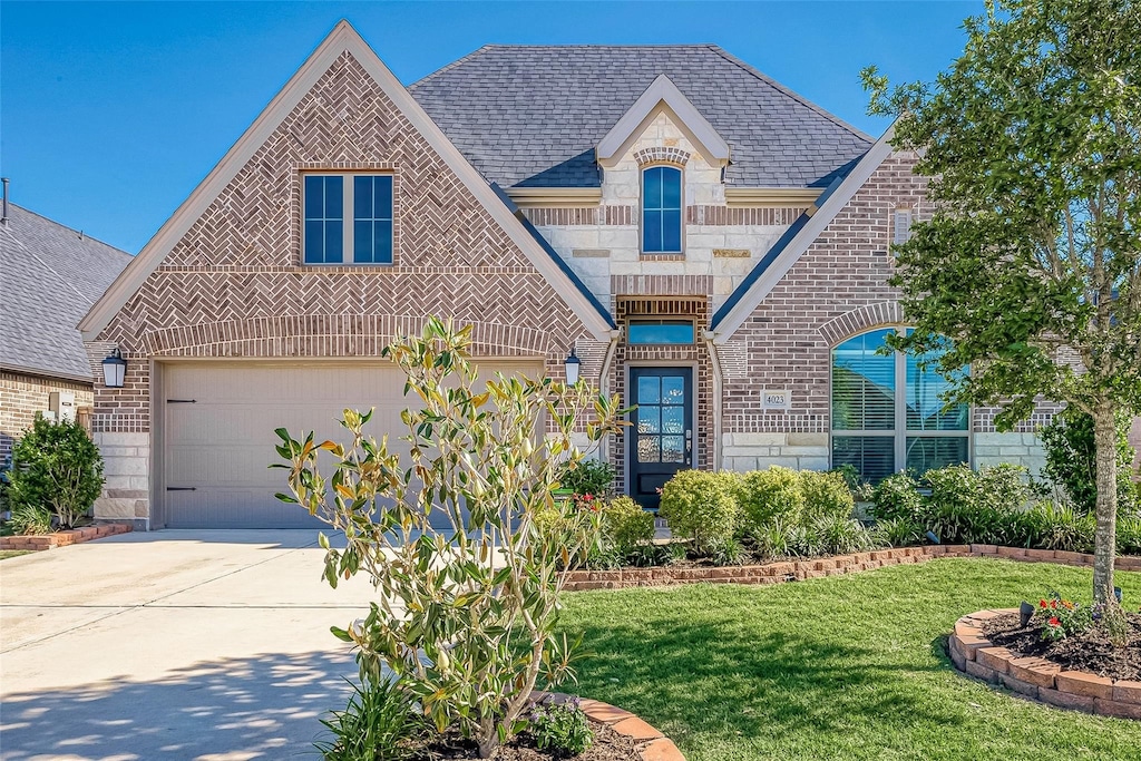 view of front of property featuring a garage, a balcony, and a front yard