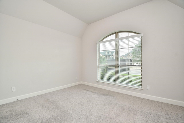 carpeted empty room featuring vaulted ceiling