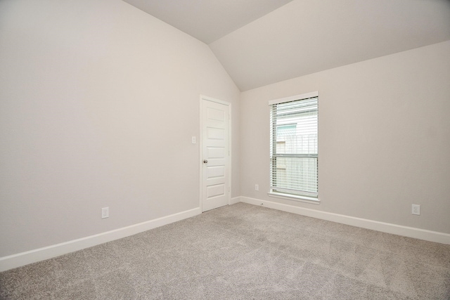 carpeted spare room with lofted ceiling