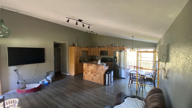 kitchen featuring appliances with stainless steel finishes, backsplash, dark hardwood / wood-style floors, hanging light fixtures, and lofted ceiling