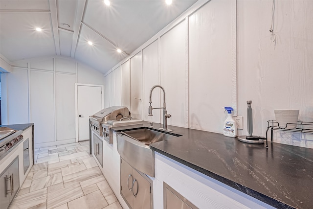 kitchen with white cabinetry, sink, and vaulted ceiling