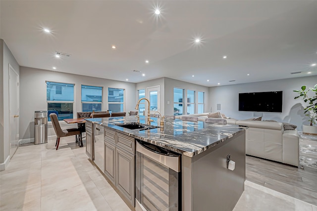 kitchen featuring stone counters, sink, wine cooler, a center island with sink, and light tile patterned flooring