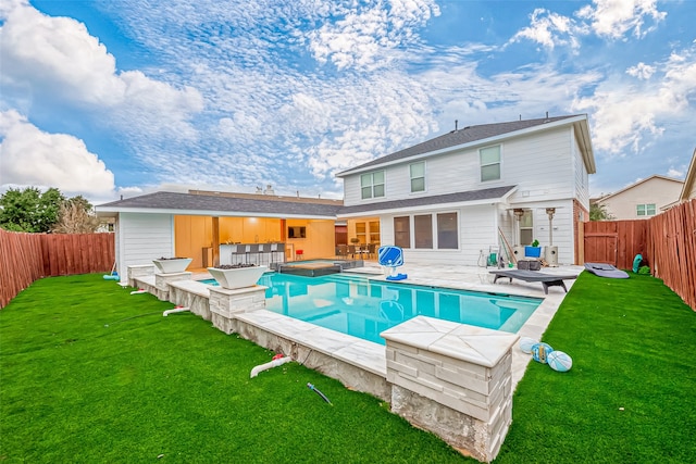 back of house with a lawn, area for grilling, a patio area, and a fenced in pool