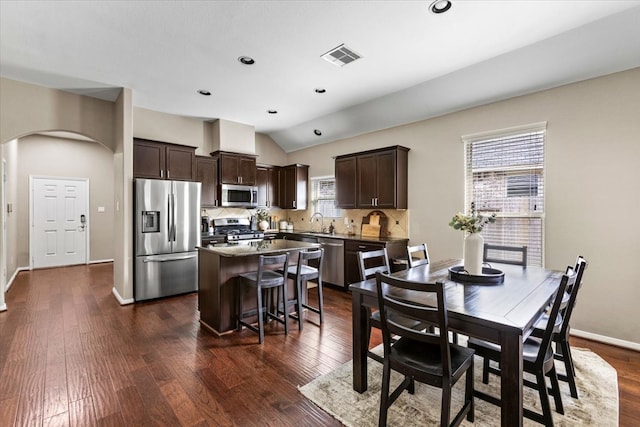 dining room featuring vaulted ceiling, a wealth of natural light, dark wood-type flooring, and sink