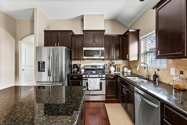 kitchen featuring sink, stainless steel appliances, dark hardwood / wood-style flooring, dark stone counters, and decorative backsplash