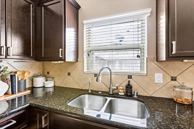 kitchen featuring dark brown cabinets, backsplash, dark stone counters, and sink