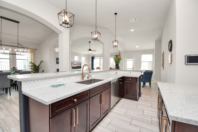 kitchen with ceiling fan, sink, light stone counters, a large island with sink, and pendant lighting