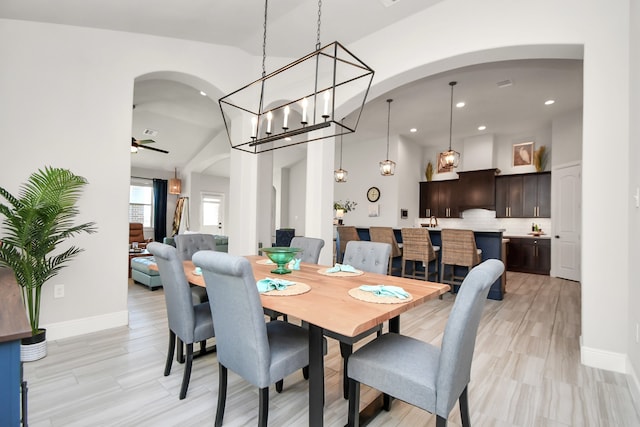 dining space with ceiling fan, light wood-type flooring, and vaulted ceiling