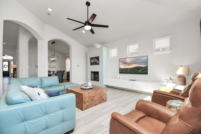 living room with lofted ceiling, light hardwood / wood-style floors, and ceiling fan with notable chandelier