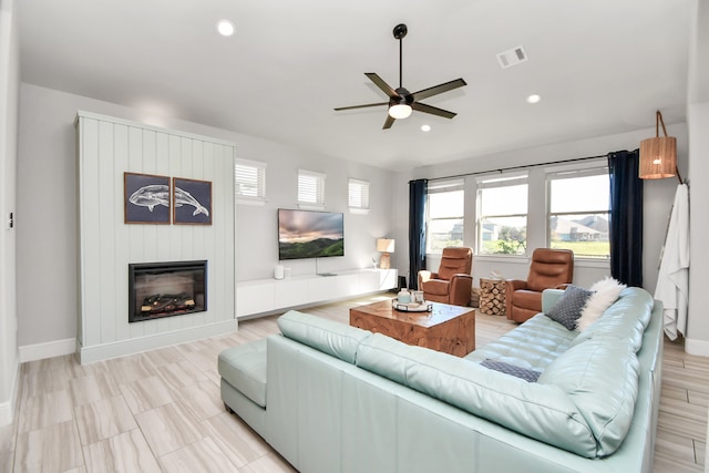 living room featuring a large fireplace and ceiling fan