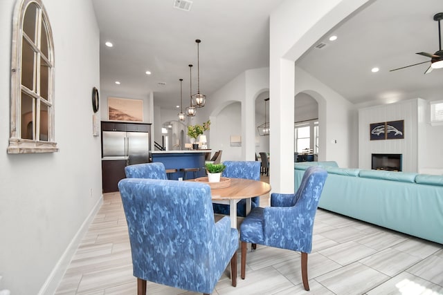 dining area with a fireplace, light wood-type flooring, and ceiling fan