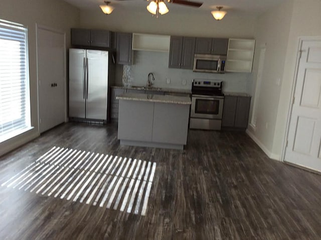 kitchen with a center island, stainless steel appliances, gray cabinets, and dark hardwood / wood-style floors