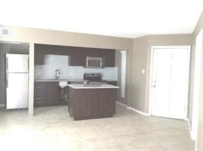 kitchen featuring dark brown cabinets, sink, a kitchen island, and white appliances