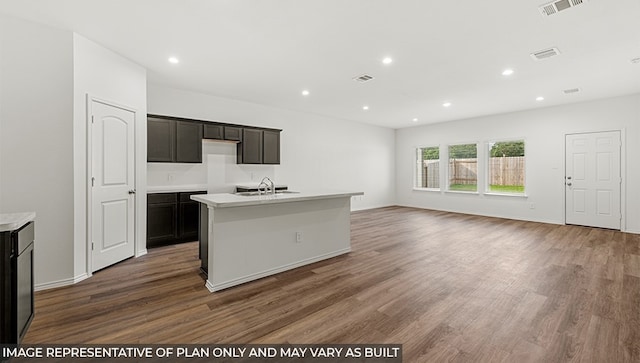 kitchen featuring a center island with sink, dark hardwood / wood-style flooring, dark brown cabinetry, and sink