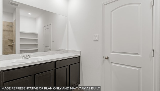 bathroom featuring a tile shower and vanity