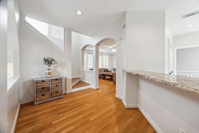 hallway with decorative columns and light hardwood / wood-style floors