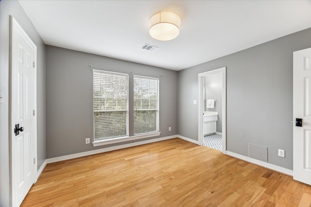 unfurnished bedroom with ensuite bath and light hardwood / wood-style flooring