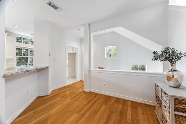 hallway featuring light wood-type flooring and lofted ceiling