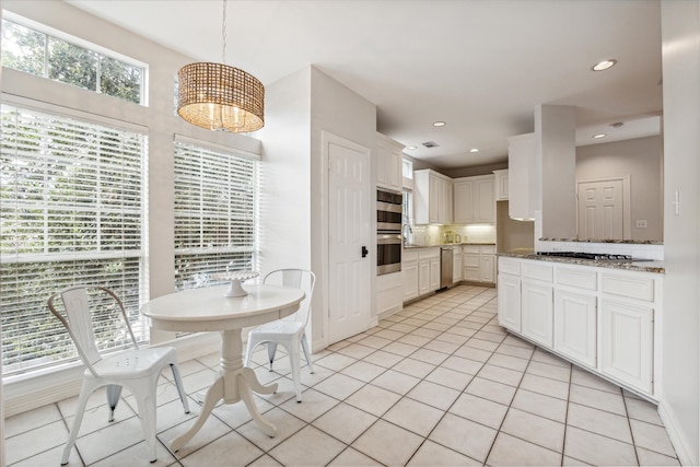 kitchen with light stone counters, stainless steel appliances, pendant lighting, white cabinets, and light tile patterned flooring