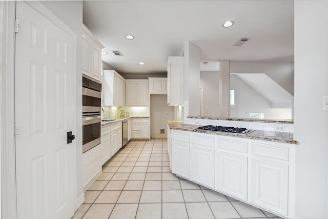 kitchen with white cabinetry, light stone countertops, stainless steel appliances, decorative backsplash, and light tile patterned flooring