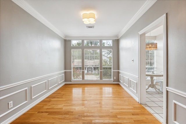 spare room featuring a chandelier, light wood-type flooring, and ornamental molding