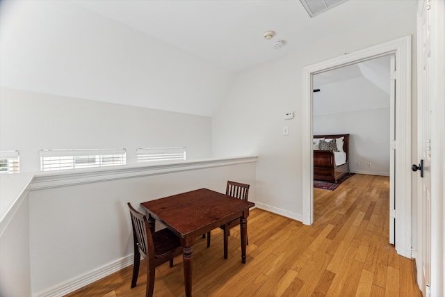 dining space with light hardwood / wood-style floors and vaulted ceiling