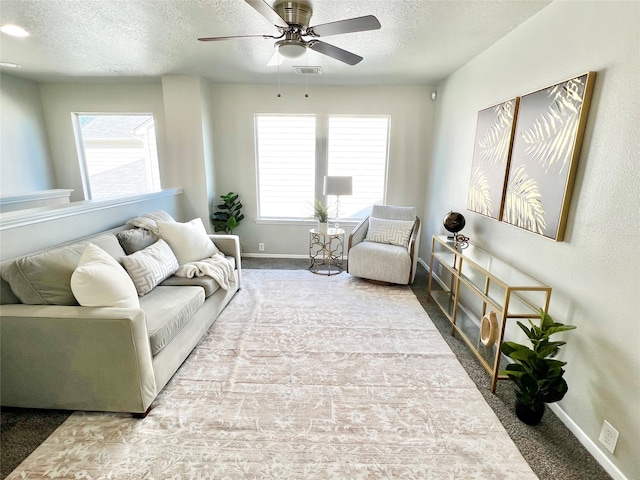 living room with carpet flooring, ceiling fan, and a textured ceiling