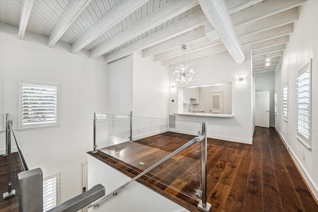 interior space featuring an inviting chandelier, beam ceiling, a wealth of natural light, and wood-type flooring