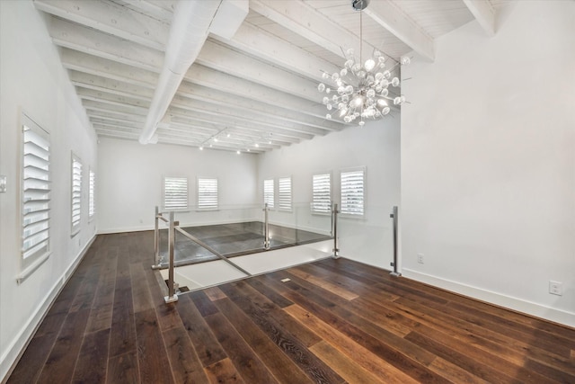 spare room with dark wood-type flooring, a notable chandelier, and beam ceiling