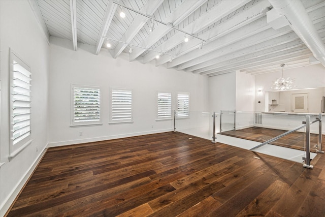 empty room with rail lighting, an inviting chandelier, dark hardwood / wood-style floors, wooden ceiling, and beamed ceiling