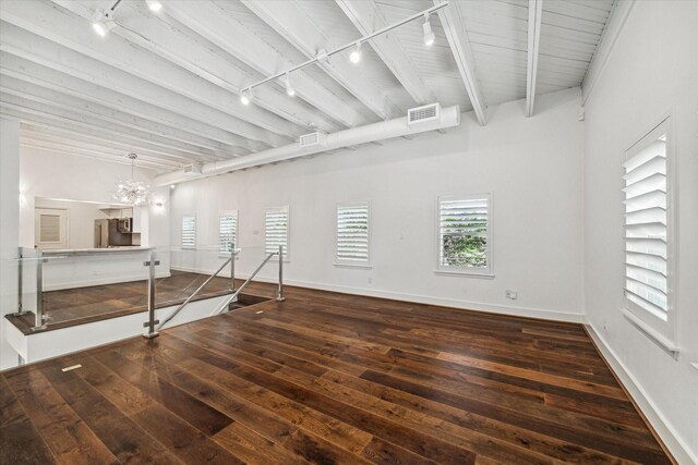 spare room featuring dark hardwood / wood-style flooring, beamed ceiling, track lighting, and a notable chandelier