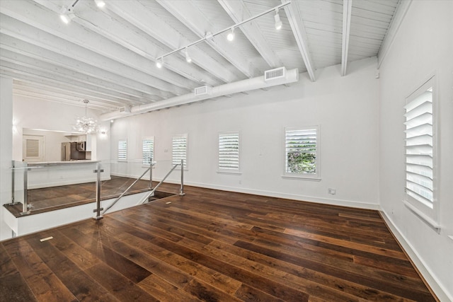 spare room with a notable chandelier, dark wood-type flooring, rail lighting, and beamed ceiling