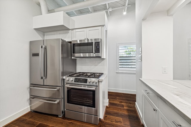 kitchen with stainless steel appliances, light stone countertops, white cabinets, dark hardwood / wood-style flooring, and decorative backsplash