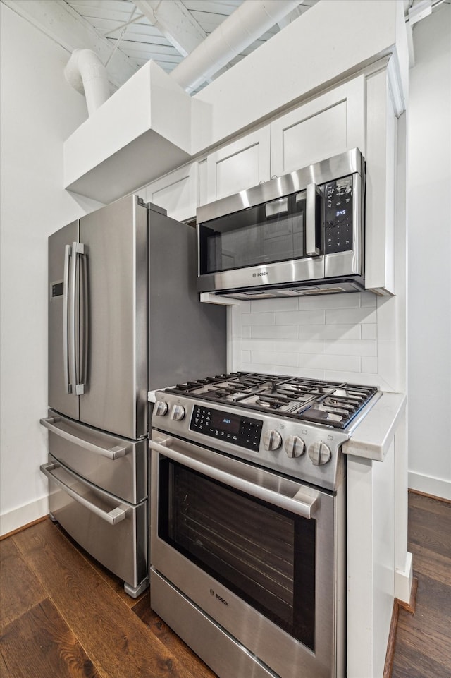 kitchen with dark wood-type flooring, white cabinetry, stainless steel appliances, and decorative backsplash