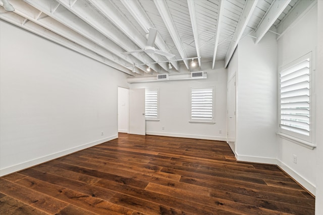 empty room with dark wood-type flooring and beam ceiling