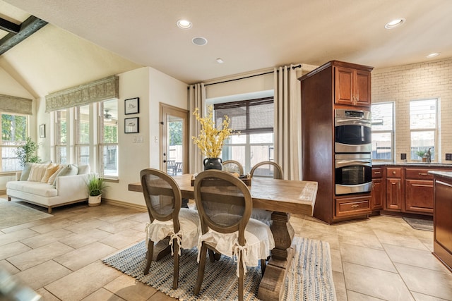 tiled dining space with a wealth of natural light, sink, brick wall, and lofted ceiling