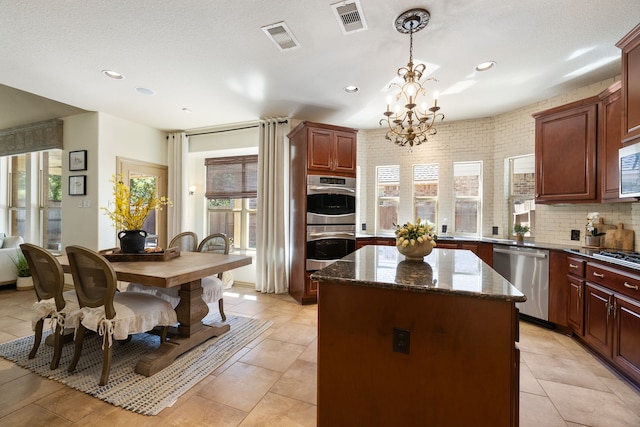 kitchen with stainless steel appliances, a kitchen island, plenty of natural light, and dark stone counters