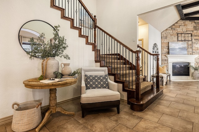 stairs with beamed ceiling, a stone fireplace, and high vaulted ceiling