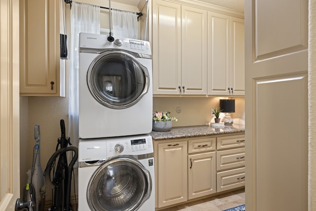 laundry area with cabinets and stacked washer and clothes dryer