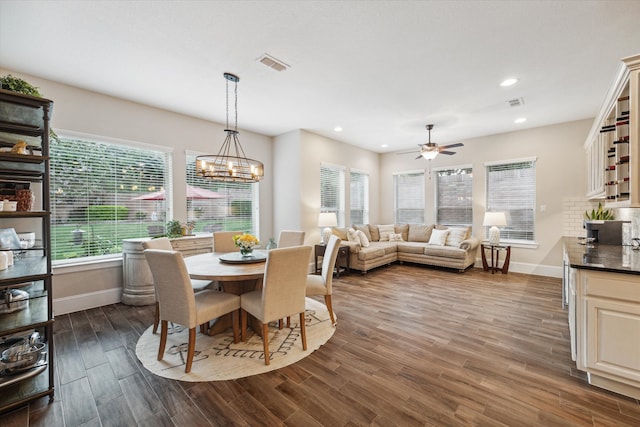 dining space with ceiling fan with notable chandelier, dark hardwood / wood-style flooring, and a wealth of natural light