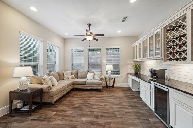 living room with wine cooler, ceiling fan, and dark wood-type flooring