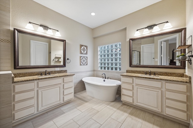 bathroom featuring a tub to relax in, vanity, and tile walls