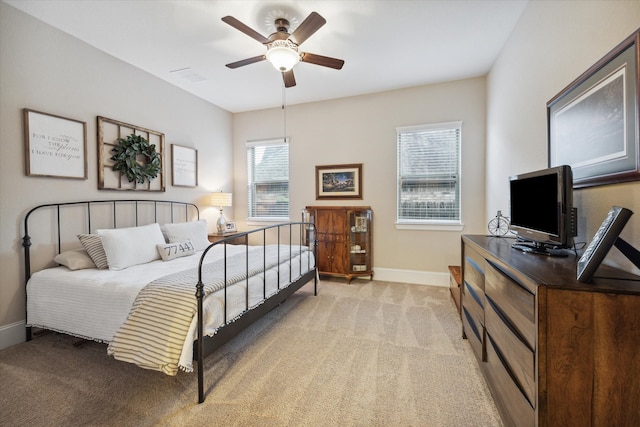 carpeted bedroom featuring multiple windows and ceiling fan