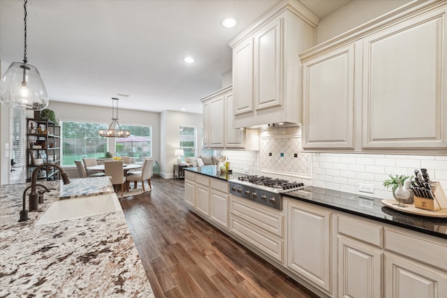 kitchen with sink, dark hardwood / wood-style floors, dark stone countertops, decorative light fixtures, and stainless steel gas stovetop