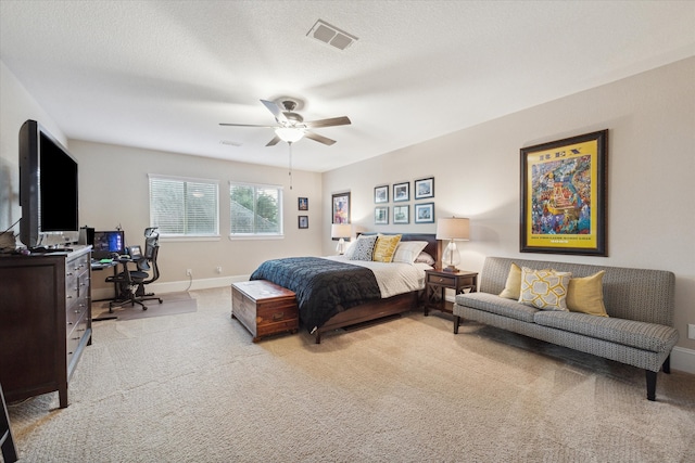 bedroom with ceiling fan, light carpet, and a textured ceiling