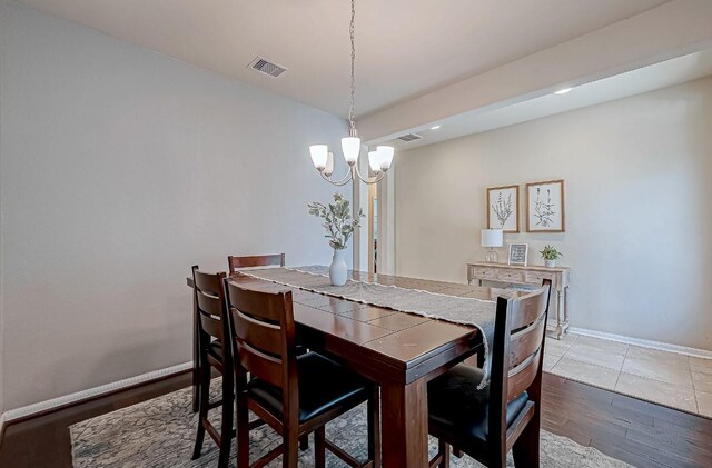 dining room with hardwood / wood-style flooring and an inviting chandelier