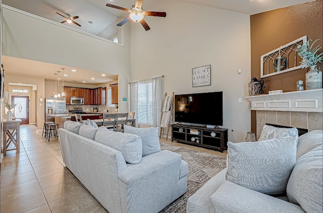 tiled living room featuring ceiling fan, a tile fireplace, and high vaulted ceiling