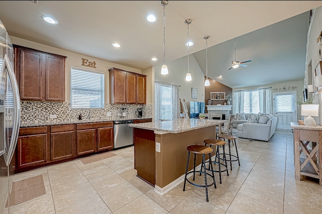 kitchen featuring ceiling fan, a center island, stainless steel appliances, a kitchen breakfast bar, and tasteful backsplash